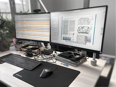 moderner Computer-Arbeitsplatz an höhenverstellbarem Schreibtisch für die Produktion digitaler Schulbuchmaterialien